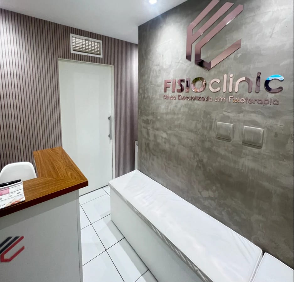 Recepção da FisioClinic com o letreiro em rosé sobre parede de cimento queimado e ripado mauve