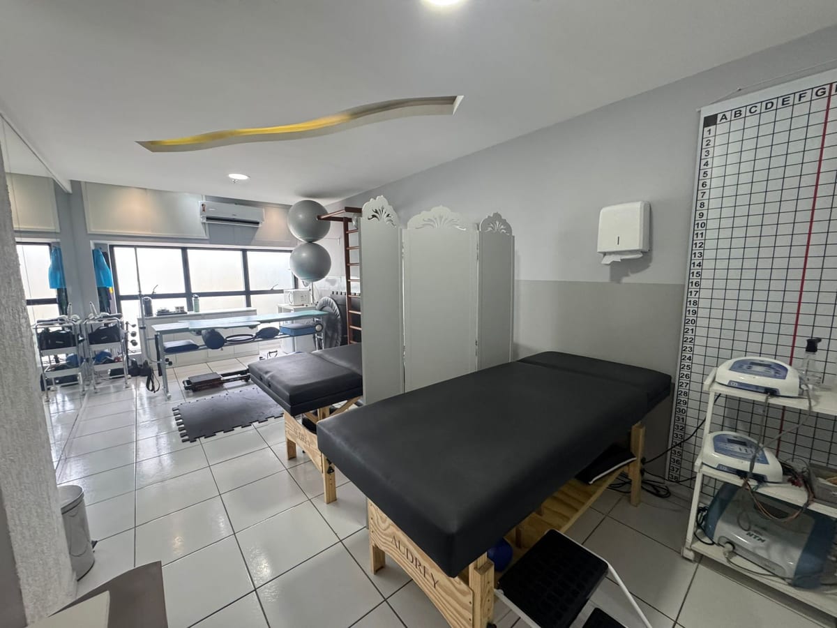 Sala de atendimento da FisioClinic com macas, aparelhos de fisioterapia, bolas e barra de parede